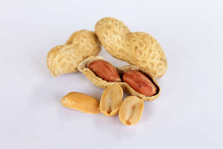 Peanuts isolated on white background . Two kernels are already unpacked. One of the peanuts unpacked...