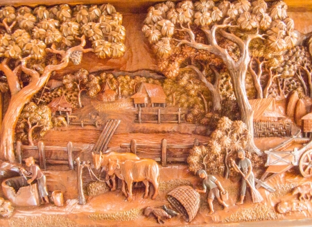 The carved teak wood shows the daily life in Thai rural area の写真素材