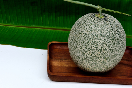 A kind of edible fleshy  melon with netted skin pattern  on wood tray.の写真素材