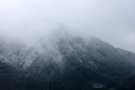 The mountain peaks covered with snow flakes and cloud .