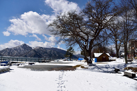 The bank of Chuzenji Lake  with snowy mountains and shedding trees in winter.の写真素材
