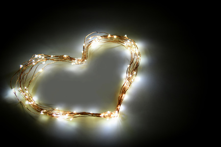 Heart shape made from twinkle lights on black background. Card design and decoration.の写真素材