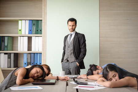 caucasian angry boss looking at employees sleeping in meeting room at office