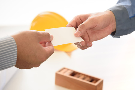 exchanging business card with engineering tools background, selective focusの写真素材