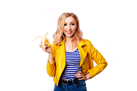 Slim blonde girl with a banana in her hands on an isolated white background.- Imageの写真素材