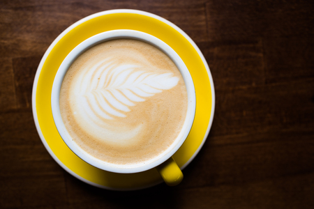 Yellow cup of aromatic coffee on a wooden table.の写真素材