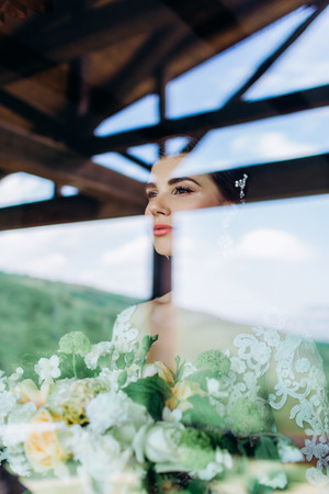 Portrait of a young girl of the bride with professional wedding makeup and hairdo in window.の写真素材