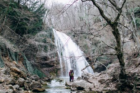 A loving, stylish, young couple in love on the background of a waterfall.の写真素材