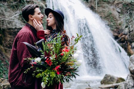 A loving, stylish, young couple in love on the background of a waterfall.の写真素材