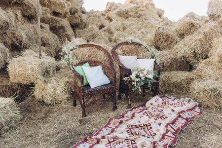 Wedding asymmetrical stylish bouquet with roses on a boho wicker chair.の写真素材