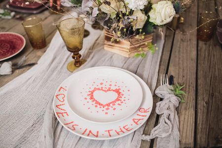 Romantic dinner of the bride and groom on a wooden table with plates and fresh flowers.の写真素材