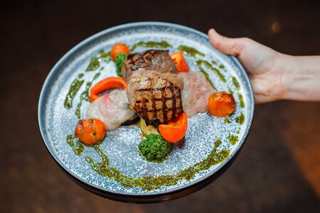 Middle-fried meat with vegetables on a blue dish in a restaurant.