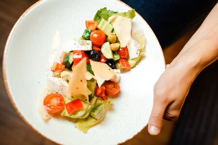 Greek salad in an original serving on a dish. Tomatoes, cheese, vegetables.