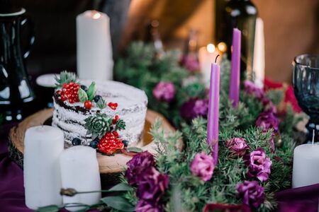 Delicate wedding white cake decorated with pomegranate and succulent surrounded by flowers and candles.の写真素材
