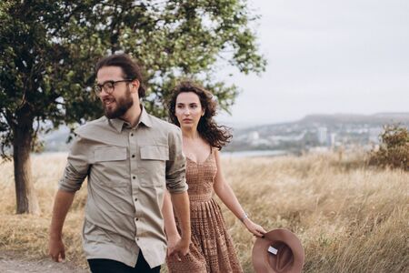Boyfriend and Girlfriend run in tall yellow grass in the forest.の写真素材