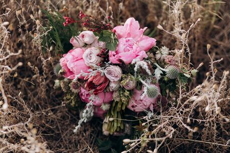 Pink wedding bouquet with a stone rose and peonies on the background of grass.の写真素材