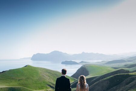 Loving girl and guy look at the mountains and the sea.
