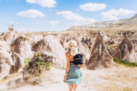 A blonde girl runs across the mountains in Turkey in Cappadocia. Follow me.の写真素材