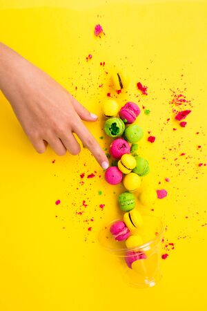 Scattered macaroons from a glass on a yellow background. Colored, bright, sweet macaroons on a yellow background.の写真素材