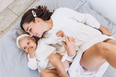 Mom and daughter play with a sheet. The baby and mom are smiling.