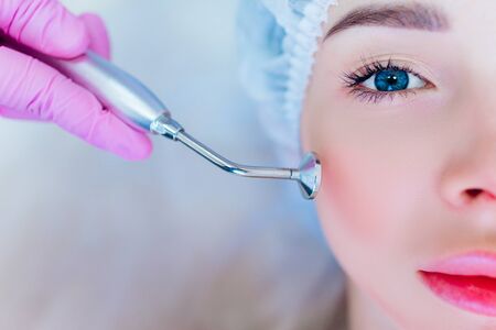 Hardware skin care. A young girl cares for her face. Beauty treatment. Procedures. Advertising.の写真素材
