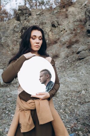 Black-haired girl with a mirror in her hands. Magic and Witchcraft.の写真素材