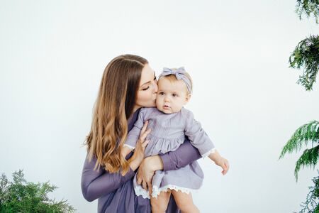 Mom smiles and kisses her daughter. A happy family. Portrait of a mother.の写真素材