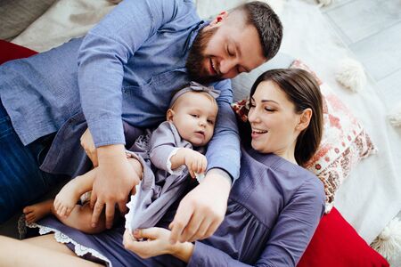 Family in blue clothes happily play with a child on the floor.の写真素材