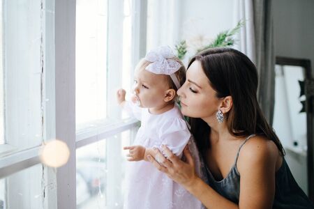 Mom smiles and kisses her daughter. A happy family. Portrait of a mother.