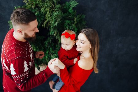 Family in red sweater clothes happily play with a child.