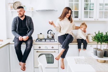 Happy family of three in a bright kitchen smiling.の写真素材