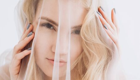Stylish portrait of a blonde girl through the fabric. View from above.