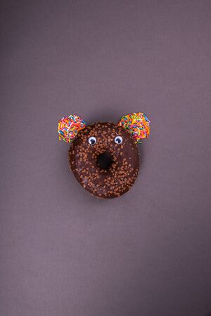 Chocolate donut with eyes on a dark background. Abstraction and minimalism.