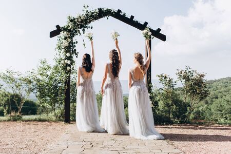 Bridesmaids in white dresses on the green grass against the backdrop of the mountains.の写真素材