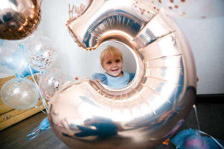 Birthday of a little blonde girl. Child in festive balloons.