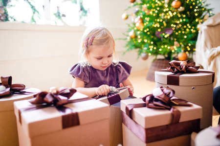 Little blonde girl surrounded by Christmas gifts.の写真素材