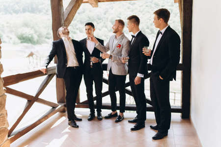 The groom and his friends celebrate the wedding. Men in suits. Mens emotions and friendship.の写真素材