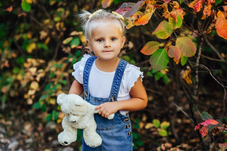 Little white girl in a white blue dress laughs in forest. Preschooler.の写真素材