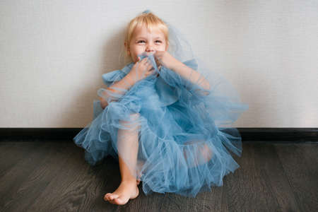 Little white girl in a blue dress laughs. Preschooler.の写真素材