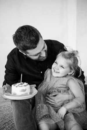 Father and dauther celebrates the birthday of their little daughter. Birthday celebration in dresses with cake.の写真素材