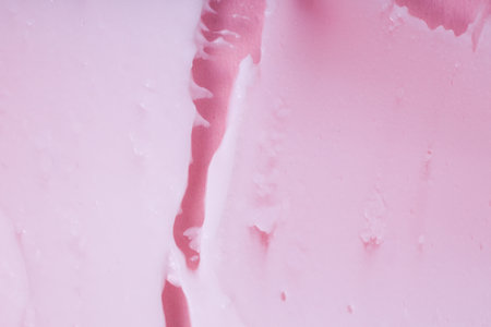 Smeared textured cream on a pink background. Macro shot of a creamy texture.の写真素材