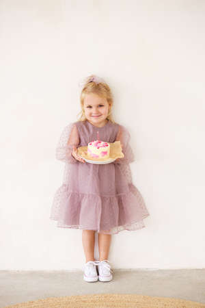 Little white Birthday girl with cake in a pink dress laughs. Preschooler.の写真素材