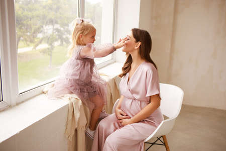 Mother and daughter in delicate outfits hug each other. Mothers Day.の写真素材