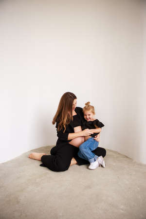 Mother and daughter in black outfits hug each other. Mothers Day.の写真素材
