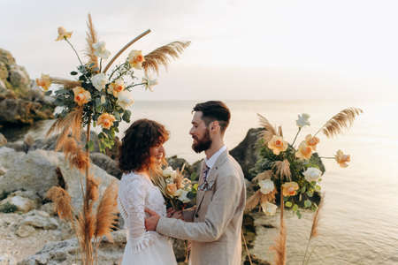 Wedding on the sunset with live floristry. Bride and groom in boho style.の写真素材