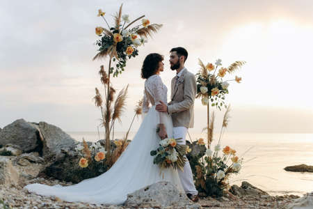 Wedding on the sunset with live floristry. Bride and groom in boho style.の写真素材