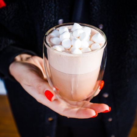 Latte in a transparent glass in the hands of a girl.の写真素材