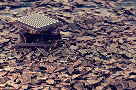Broken dark chocolate and chocolate flakes on a wooden table
