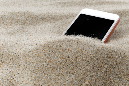 Mobile phone in sand on a beachの写真素材