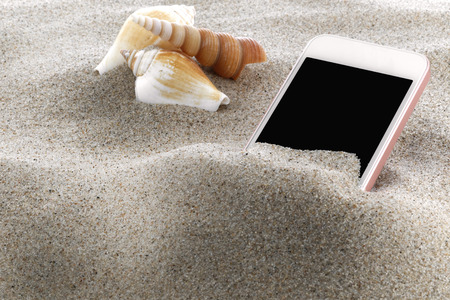 Mobile phone in sand on a beachの写真素材